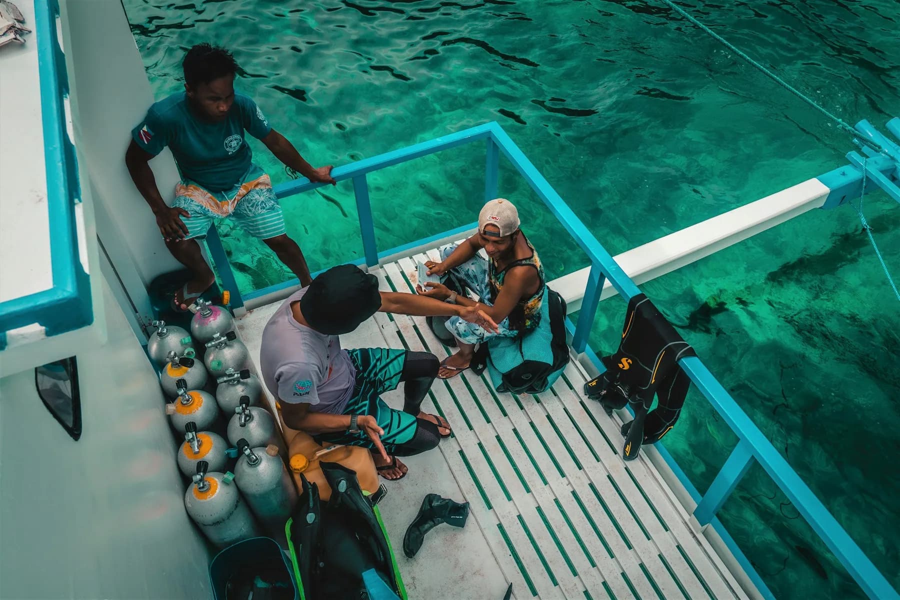 Divers preparing their equipment on a boat over clear Palawan water