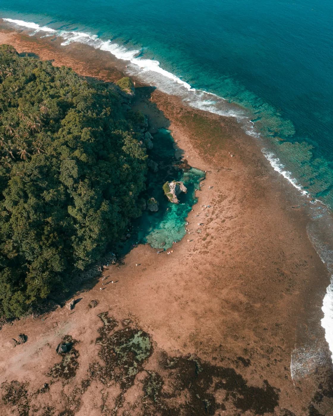 Aerial view of a clear tidal pool and rugged coast in Siargao